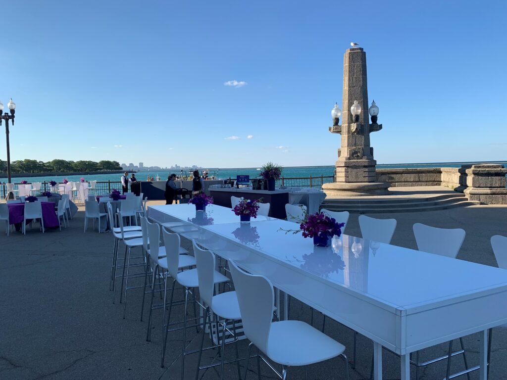 Outdoor waterfront event setup with modern white tables and chairs from a premium furniture rental service, ideal for weddings, parties, and corporate gatherings.