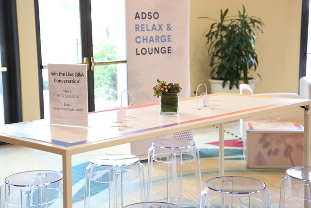 Bali White Communal Bar Table with branded vinyl tabletop in a corporate charging lounge